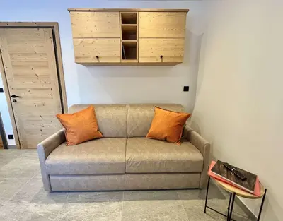 a couch with orange pillows in a living room at Appartement Studio, 2 couchages, MEGEVE MEG400-T122 in Megève