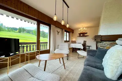 a bedroom with a bed and a living room with a tv at Balcon des cimes - 80 m in Combloux