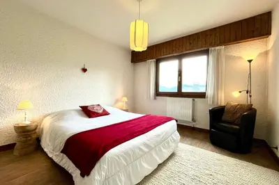 a small white room with a bed and a table at Balcon des cimes - 80 m in Combloux
