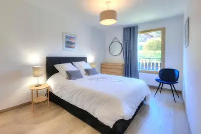 a bedroom with a large bed and a window at Open the door and Hike, Ski or Bike 3 Br Apartment Saint Gervais in Saint-Gervais-les-Bains