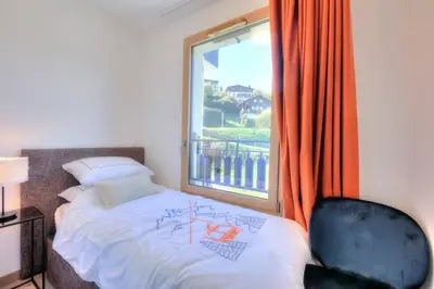 a bedroom with a bed and a window and a chair at Open the door and Hike, Ski or Bike 3 Br Apartment Saint Gervais in Saint-Gervais-les-Bains