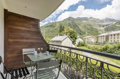 a balcony with a table and chairs and mountains at T3 Argentière in Chamonix-Mont-Blanc