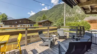 a balcony with chairs and tables and a view of a mountain at Chalet Follette in Chamonix-Mont-Blanc