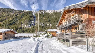 a log cabin with a deck and mountains in the background at Chalet Follette in Chamonix-Mont-Blanc