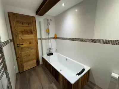 a bath tub in a bathroom with a wooden door at Beautiful chalet with panoramic views in Samoens walking distance to the village in Samoëns