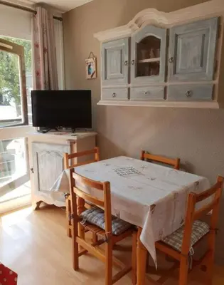 a dining room with a table and chairs and a tv at Au pied des pistes Studio 4 personnes in Morillon
