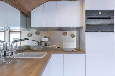 a kitchen with white cabinets and wooden floors at Résidence Le Panorama - Megève in Megève
