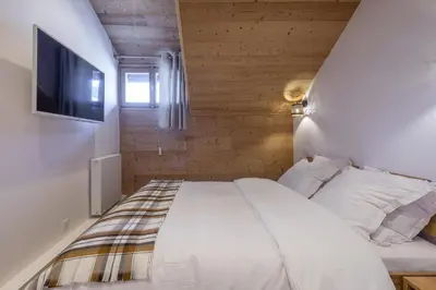a bedroom with a white bed and a tv at Résidence Le Panorama - Megève in Megève