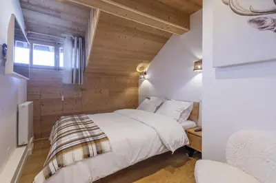 a bedroom with a bed in a room with wooden walls at Résidence Le Panorama - Megève in Megève