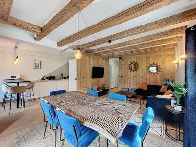 a dining room and living room with a table and blue chairs at Appartement Alpage in Les Houches