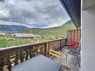 a balcony with a table and chairs and mountains at Appartement Alpage in Les Houches