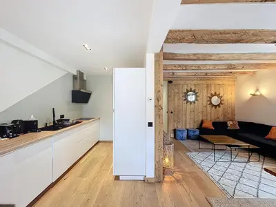 a kitchen and living room with white walls and wooden floors at Appartement Alpage in Les Houches