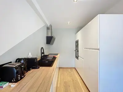 a kitchen with white walls and a counter with a refrigerator at Appartement Alpage in Les Houches