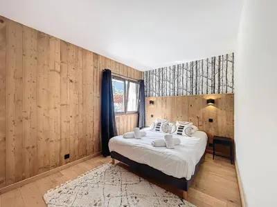a bedroom with a bed in a room with wooden walls at Appartement Alpage in Les Houches