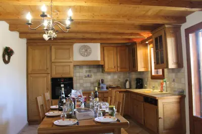 a kitchen with wooden cabinets and a table with dishes on it at La Ferme de Sous-Lachat in Samoëns