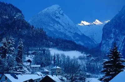 a snowy mountain with a village and a lake at La Ferme de Sous-Lachat in Samoëns
