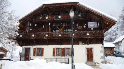 a house covered in snow with a light pole at La Ferme de Sous-Lachat in Samoëns