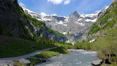 a mountain valley with a river and snow covered mountains at La Ferme de Sous-Lachat in Samoëns