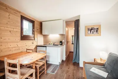 a kitchen and living room with a table and a couch at Studio Lanchettes - Your stay at the gates of Megève in Demi-Quartier