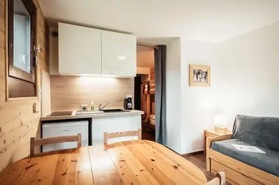 a kitchen and a living room with a table and a couch at Studio Lanchettes - Your stay at the gates of Megève in Demi-Quartier