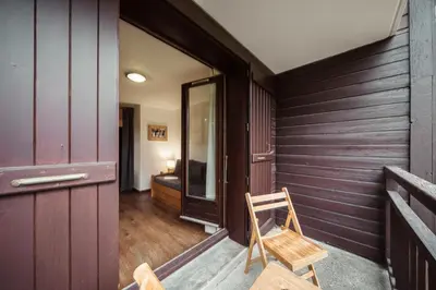 a wooden chair sitting on the porch of a house at Studio Lanchettes - Your stay at the gates of Megève in Demi-Quartier