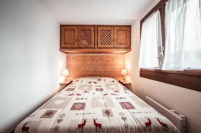 a small bedroom with a bed with a quilt on it at Studio Lanchettes - Your stay at the gates of Megève in Demi-Quartier