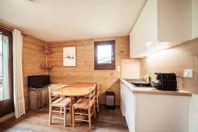 a kitchen with a wooden table and chairs in a room at Studio Lanchettes - Your stay at the gates of Megève in Demi-Quartier