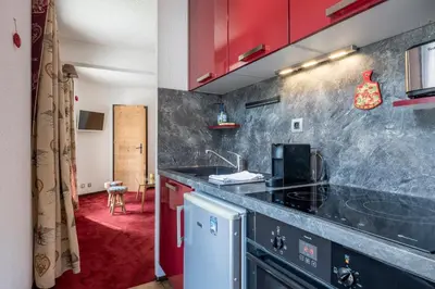 a kitchen with red cabinets and a black counter top at Apartment l'Aiguille, au pied des télécabines in Chamonix-Mont-Blanc