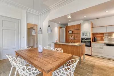 a kitchen with a wooden table and white chairs at Majestic Chamonix in Chamonix-Mont-Blanc