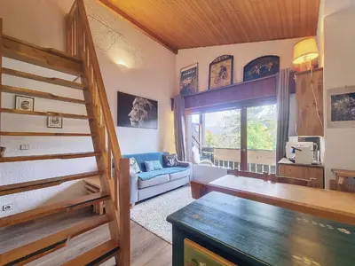 a living room with stairs and a couch and a window at Duplex 2 pièces avec balcon et Wifi face au Mont Blanc - FR-1-560-165 in Combloux