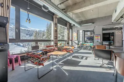 a woman standing on top of a building with a drink at Totem, Friendly Hotel & Spa in Flaine