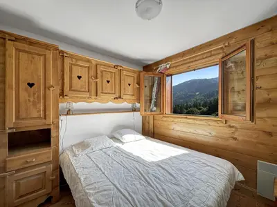 a bedroom with a bed and a window at TRAA15 Appartement 3 pieces proximite ski bus in Les Carroz d'Araches