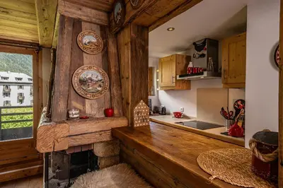 a kitchen with a wooden wall with a fireplace at La Cachette - Mountain style and spacious 2-Bed apartment central Chamonix in Chamonix-Mont-Blanc