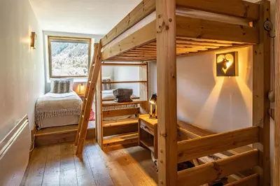 a bedroom with a bunk bed in a room with wooden floors at La Cachette - Mountain style and spacious 2-Bed apartment central Chamonix in Chamonix-Mont-Blanc
