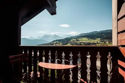 a table on a balcony with a view of mountains at Le Cocon - Balcon sur le Mont-Blanc in Combloux