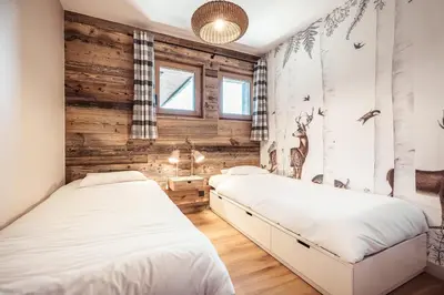 two beds in a bedroom with wooden walls at Le Cocon - Balcon sur le Mont-Blanc in Combloux