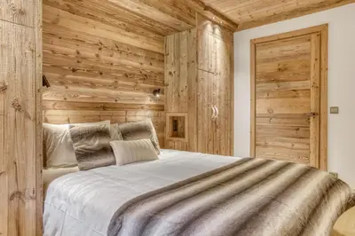 a bedroom with wooden walls and a large bed at Glacier in Megève