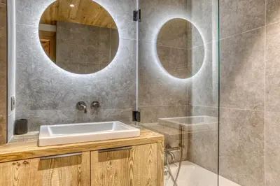 a bathroom with a sink and two round mirrors at Glacier in Megève