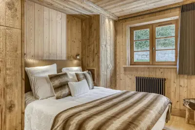 a bedroom with a bed in a room with wooden walls at Glacier in Megève