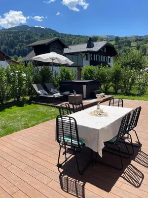 a table with chairs and an umbrella on a patio at Chalet avec Jacuzzi vue Dômes de Miage in Bionnay