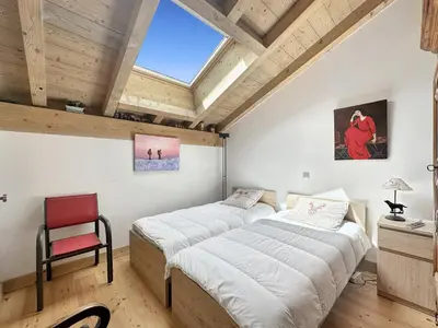 a bedroom with two beds and a red chair at ELI422 Appartement standing 6 pers centre village in Les Carroz d'Araches