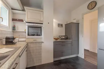 a kitchen with stainless steel appliances and a clock on the wall at Le Montagny Sejour Cosy au Coeur des Alpes in Sallanches