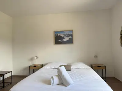 a bedroom with a white bed with two tables and a painting at Le Montagny Sejour Cosy au Coeur des Alpes in Sallanches