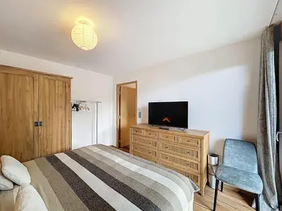a bedroom with a bed and a tv and a chair at Charmant appartement à Combloux près des pistes avec parking - FR-1-560-166 in Combloux