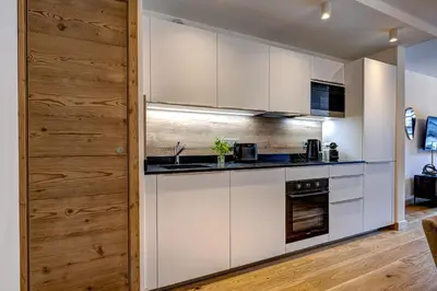 a kitchen with white cabinets and a wooden wall at Residence Blanc Mont Blanc in Chamonix-Mont-Blanc
