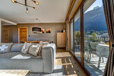 a living room with a couch and a balcony at Residence Blanc Mont Blanc in Chamonix-Mont-Blanc