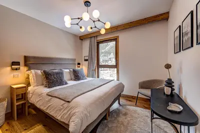 a bedroom with a bed and a table and a window at Residence Blanc Mont Blanc in Chamonix-Mont-Blanc