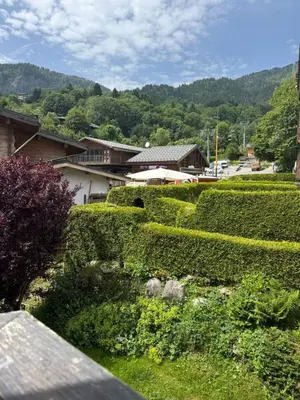 a hedge garden with a building in the background at Appartement 1 chambre, balcon, vue montagne, aux pieds des pistes in Les Houches