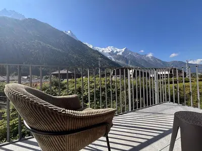 a wicker chair sitting on a balcony with a view of mountains at Blanc Mont Blanc in Chamonix-Mont-Blanc