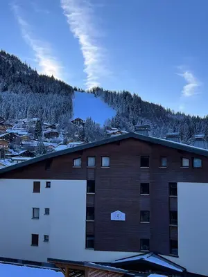 a building with a snow covered mountain in the background at Joli studio hypercentre in Les Carroz d'Araches